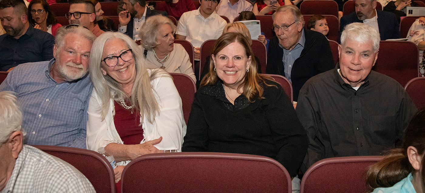 Four Tulsa Sings! audience members sit together at the Vantrease PACE auditorium smiling at the camera for a group photo.